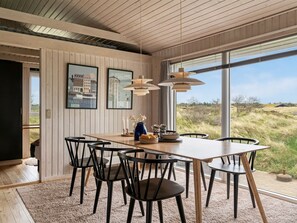 A dining area with a wooden table, black chairs, and pendant lights.