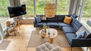 A modern living room with a sectional sofa, a round coffee table, a TV, and a wicker lamp.
