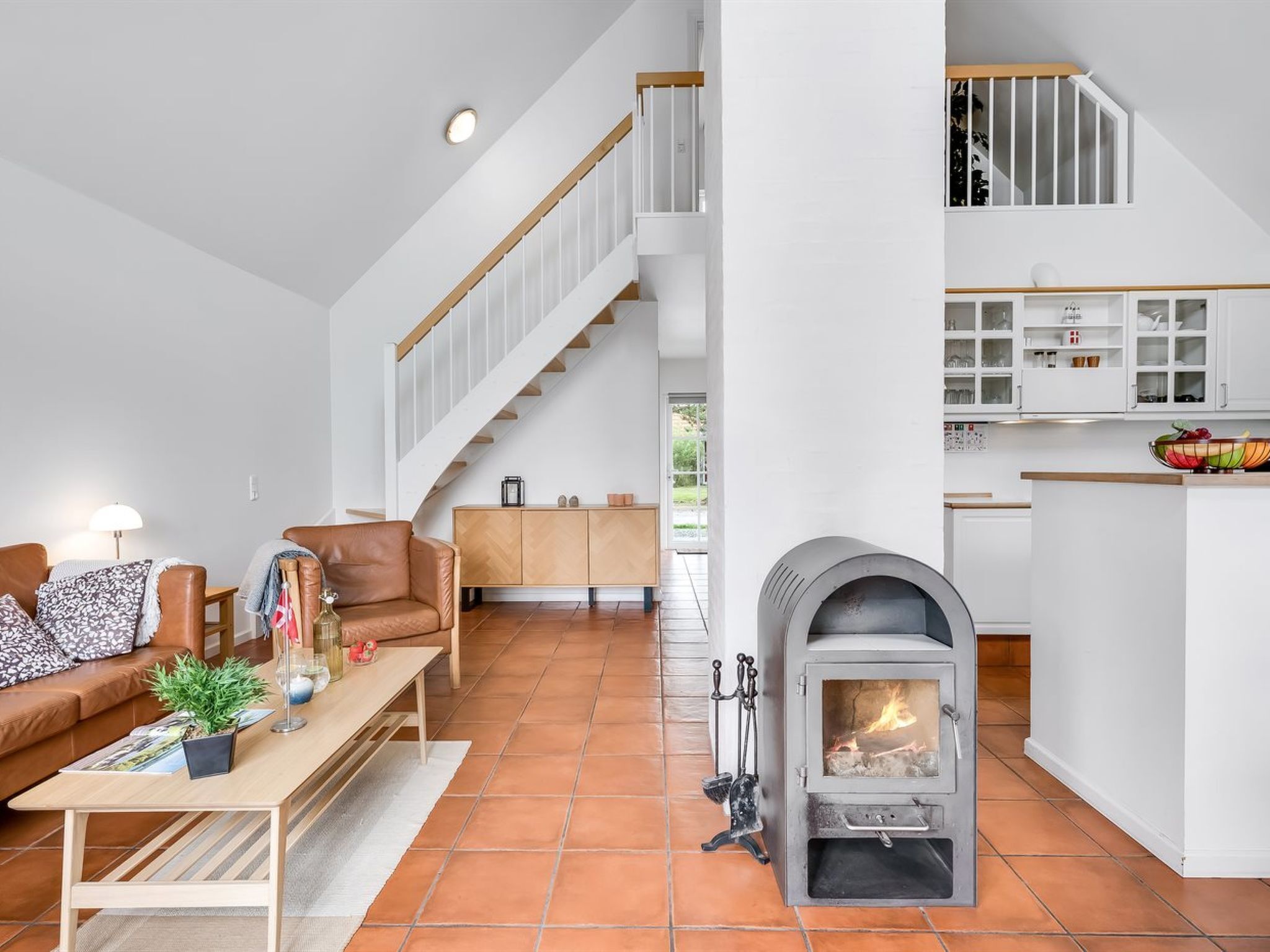 Un salon moderne avec une cheminée, un escalier et un coin cuisine.