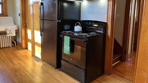 Cuina petita amb un frigorífic negre, una cuina i una campana extractora.