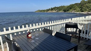 Um deck de madeira com mesa e cadeiras com vista para a praia.