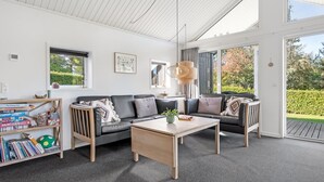 Ein modernes Wohnzimmer mit einem Ecksofa, einem Couchtisch und einem Bücherregal, das mit Büchern und einem Fußball gefüllt ist.
