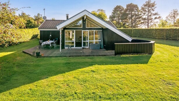 Ein modernes Haus mit geneigtem Dach, einer Terrasse und einer großen Glasdoor, die zu einem Außenbereich führt.