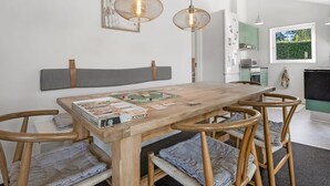 Ein Essbereich mit einem Holztisch, gestreift gepolsterten Stühlen und Pendelleuchten.