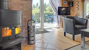 Una sala de estar acogedora con una chimenea de ladrillo, un televisor montado en la pared y un sofá confortable.