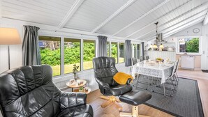 Une pièce spacieuse comprenant un coin repas, un canapé en cuir noir et une vue sur l’extérieur.