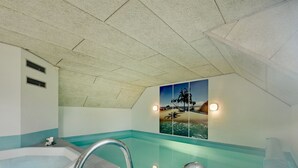 A bathroom with a large bathtub, a shower area, and a wall-mounted picture of a beach scene. - "Joona" - 12km from the sea by Interhome (Oksbøl)