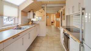 Une cuisine moderne avec des poutres en bois, une grande fenêtre et une vue sur l’extérieur.