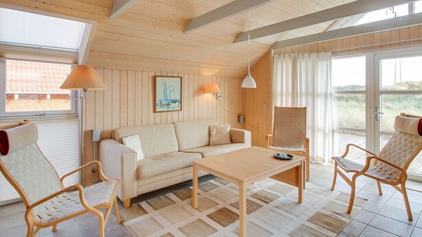 Une pièce chaleureuse avec un plafond en bois, un canapé, une table basse et deux fauteuils.