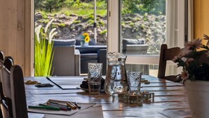 Un coin repas avec une table dressée pour deux personnes, agrémenté d’un vase de fleurs, d’un chandelier et d’une carafe en verre.