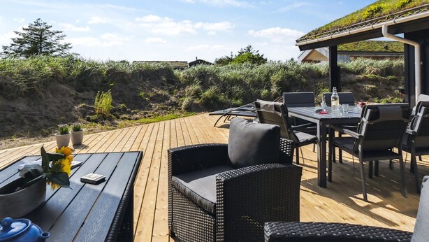 Une terrasse extérieure avec une table et des chaises, un ordinateur portable et une bouteille d’eau.