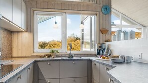 Une cuisine moderne avec une grande fenêtre, un évier et une horloge au mur.