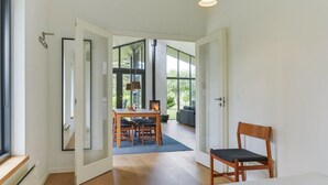 Een moderne slaapkamer met een groot bed, een houten stoel en een zithoek met een tafel en stoelen.