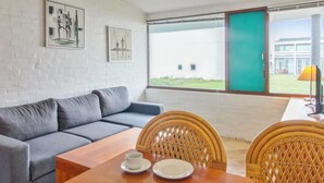 A modern room with a grey sofa, wooden dining table, wicker chairs, and artwork on the walls. - "Tatianna" - 500m from the sea by Interhome (Rømø)