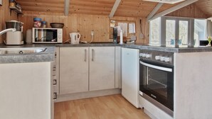 A modern kitchen with wooden walls, a built-in oven, a microwave, and a sink. - "Carlotta" - 12km from the sea by Interhome (Oksbøl)