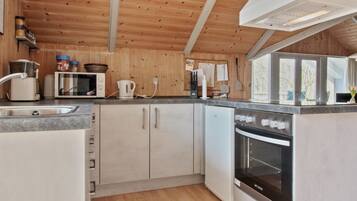 A modern kitchen with wooden walls, a built-in oven, a microwave, and a sink.