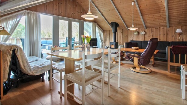 A spacious loft-style room with a high ceiling, wooden beams, a dining area with a table and chairs, a sofa, and a fireplace. - "Carlotta" - 12km from the sea by Interhome (Oksbøl)