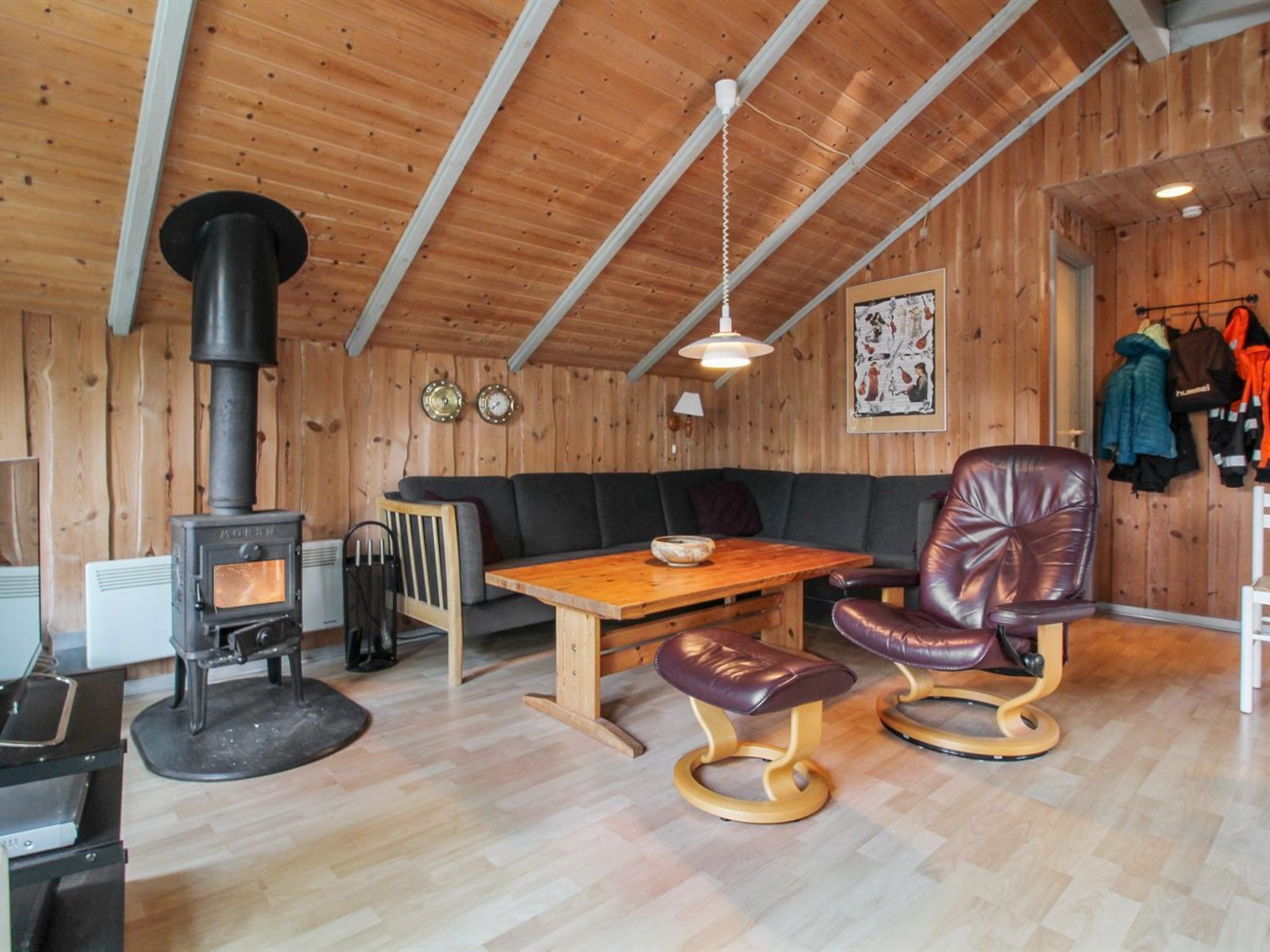 A cozy cabin interior with a wood stove, leather seating, and a dining table.