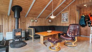 A cozy cabin interior with a wood stove, leather seating, and a dining table.