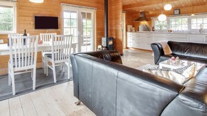 Ein gemütliches Blockhaus-Interieur mit Essbereich, einer Couch, einem Kamin und einer Küche.