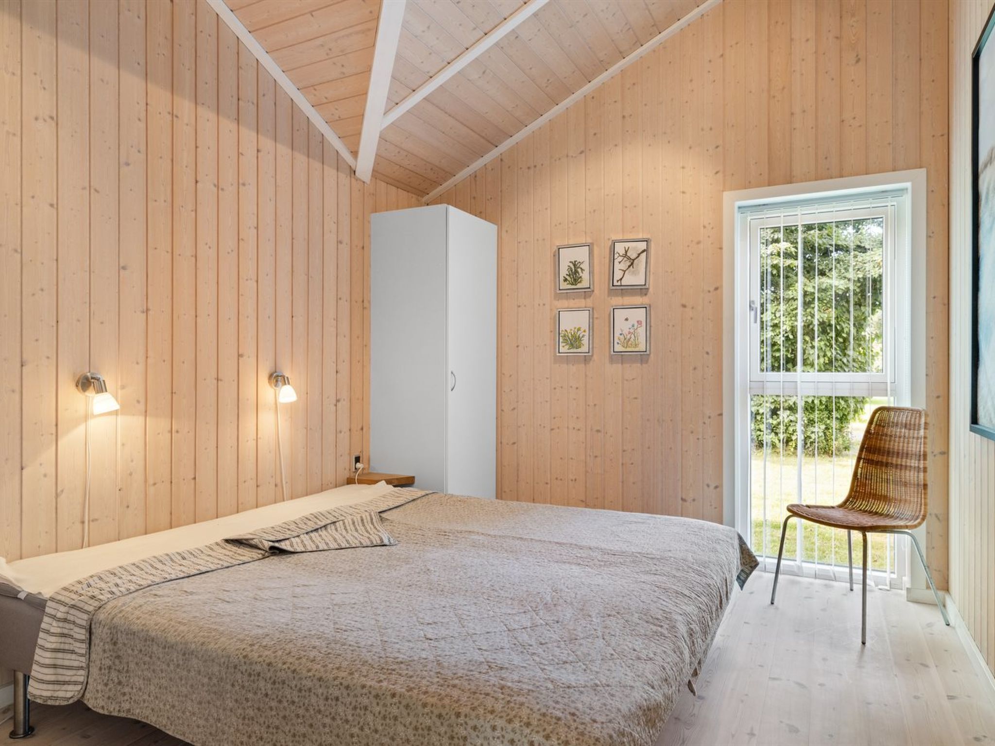 Ein Schlafzimmer mit einem großen Bett, einem Fenster mit Blick auf Grünflächen und einem Sessel am Fenster.