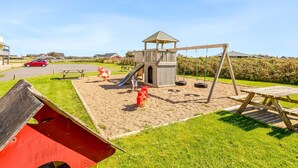 Een speeltuin met een glijbaan, schommels en een houten constructie.