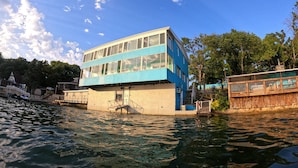 A multi-story building with a blue exterior, situated by a body of water. - Lakefront living on the 4MM - Best views on the Lake! (Rocky Mount)