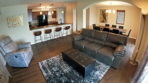 A living room with a sofa, armchair, ottoman, and a bar area with stools. - Lakefront living on the 4MM - Best views on the Lake! (Rocky Mount)