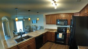 A modern kitchen with wooden cabinets, a built-in microwave, a black refrigerator, and a granite countertop. - Lakefront living on the 4MM - Best views on the Lake! (Rocky Mount)