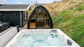 Ein Whirlpool in einem Garten mit Blick auf ein Haus und eine Hügelkette.
