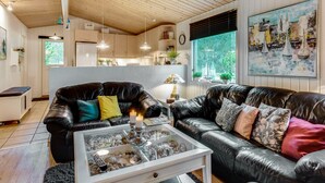 A modern living room with leather sofas, a glass coffee table, and a painting of sailboats.