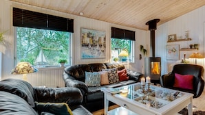 A cozy living room with a fireplace, leather sofas, and a glass coffee table.