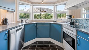 Una cucina moderna con mobili blu, un pavimento piastrellato di nero e un'ampia finestra con un ombrello.