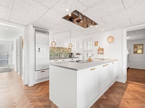 A modern kitchen with a central island, pendant lighting, and a visible ceiling vent.