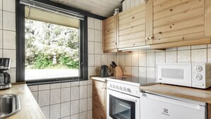 A modern kitchen with wooden cabinets, a built-in oven, a microwave, and a coffee maker. - "Biergh" - 600m from the sea by Interhome (Løkken)