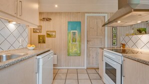 A modern kitchen with wooden cabinets, a central island, and a large painting on the wall.