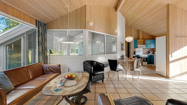 Ein modernes Interieur mit Holzboden, einem Essbereich mit Marmortisch, einer Couch und einer Küche im Hintergrund.