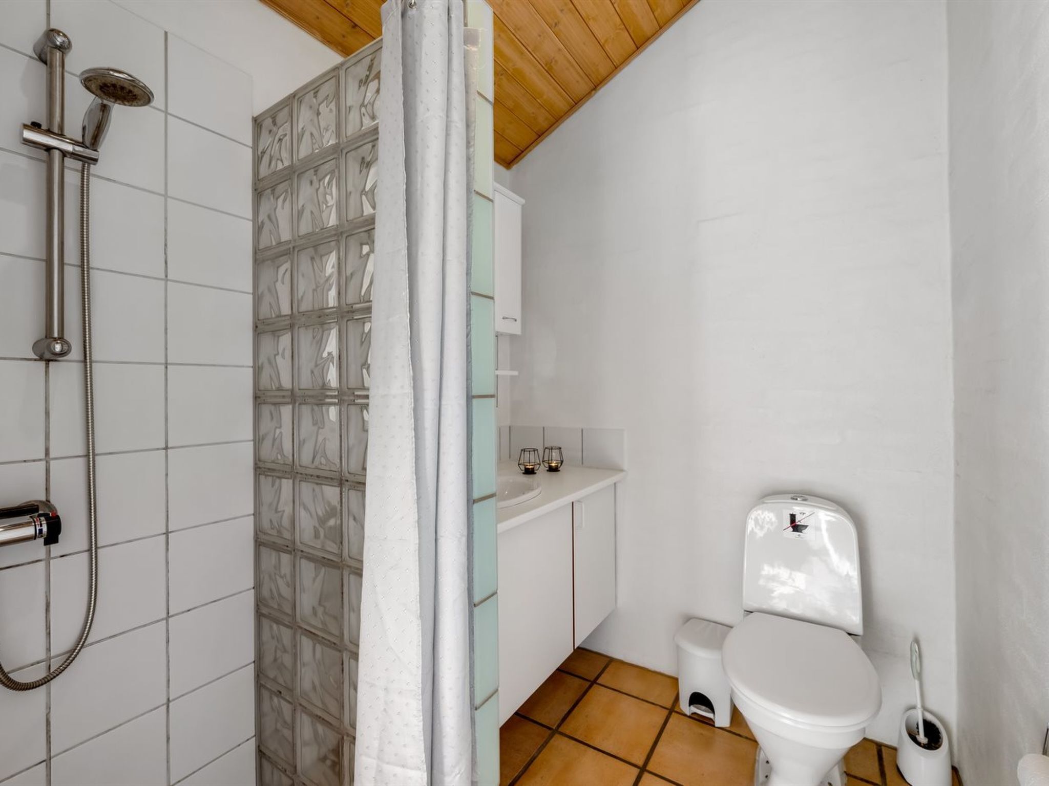 A bathroom with a shower, toilet, and a small sink.