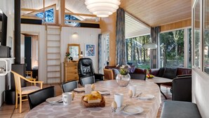 Ein modernes Interieur mit Essbereich, Holzbalkendecke und großen Fenstern.