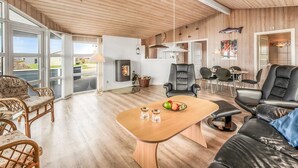 Amplia sala de estar con techo de madera, chimenea y comedor con muebles modernos.
