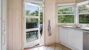 A modern kitchen with wooden walls, a large window, and a view of greenery outside.
