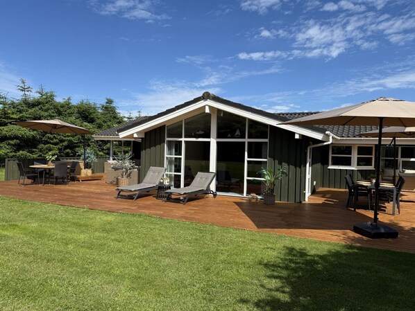 A modern house with a patio, a covered outdoor seating area, and a large glass window.
