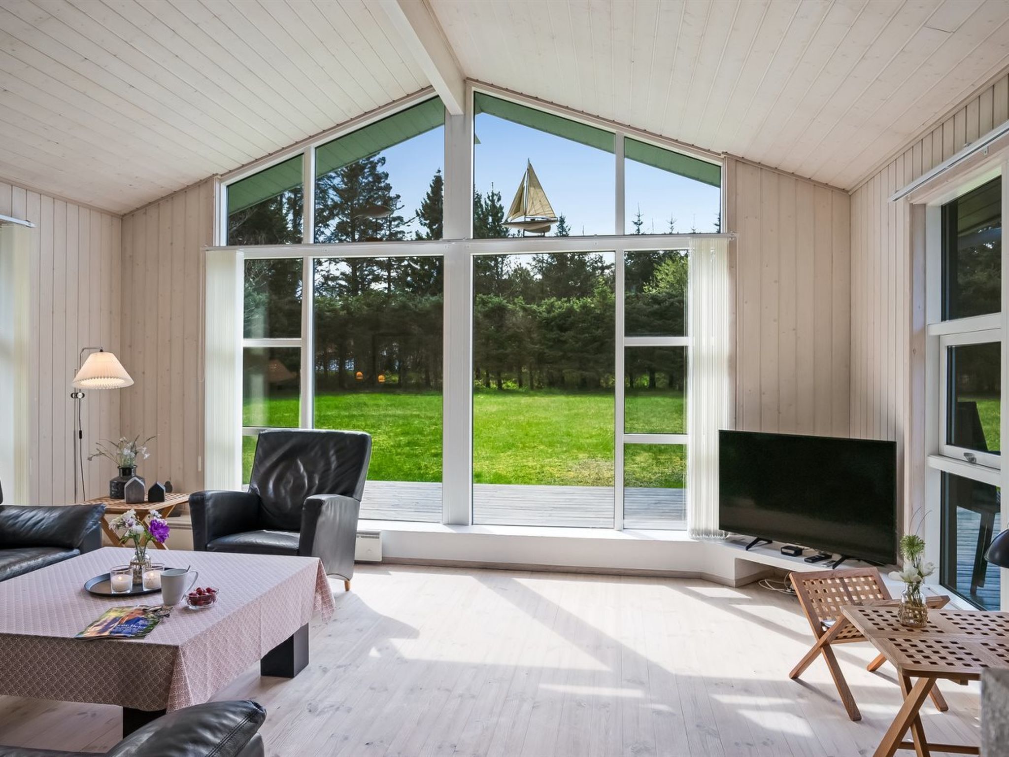 A spacious room with a large window, a television, and a cozy seating area with a table and chairs.