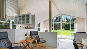 A spacious living area with a high ceiling, large windows, and a view of the outdoors.