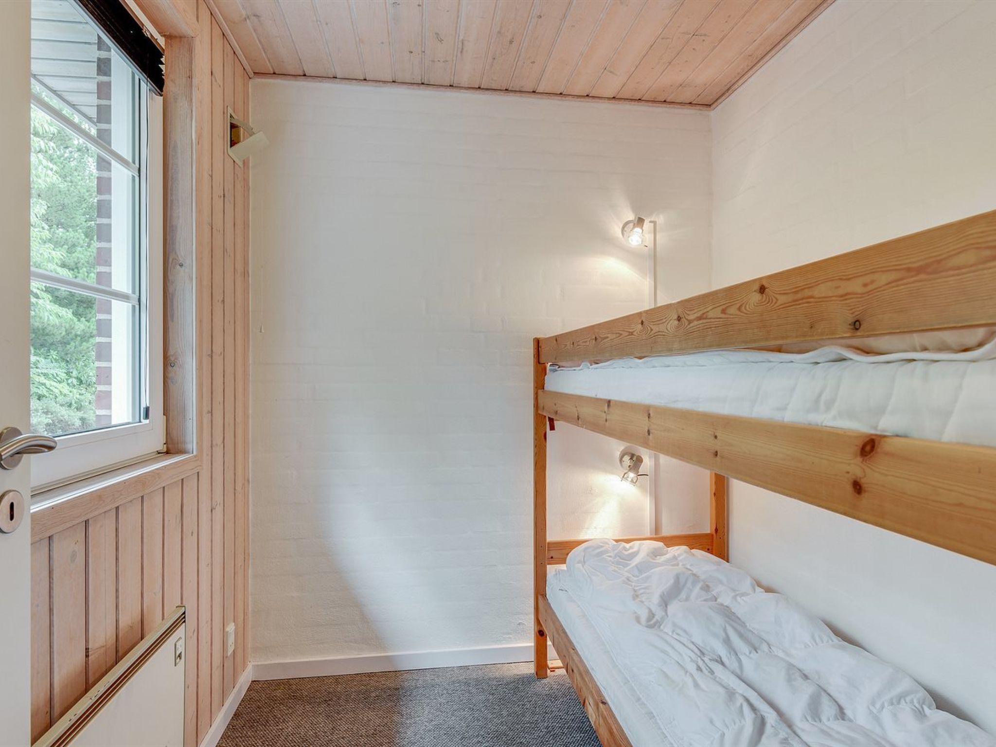 A small, single-room cabin with a bunk bed, a window, and a door.