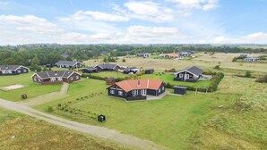 Un quartier résidentiel composé de plusieurs maisons, dont une maison principale avec un toit rouge, le tout entouré d’un paysage verdoyant.