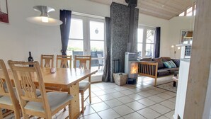 Un vaste espace de vie doté d’une cheminée, de meubles en bois et de grandes fenêtres.