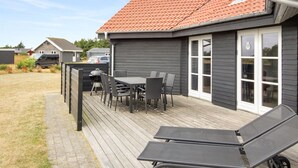 Une maison avec une terrasse, du mobilier d’extérieur et une cheminée.