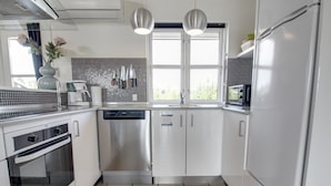 Une cuisine moderne avec des meubles blancs, un lave-vaisselle, une cuisinière et un réfrigérateur.