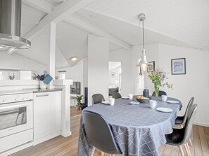 A modern kitchen with white cabinetry, a stainless steel range hood, and a dining area with a table set for two.